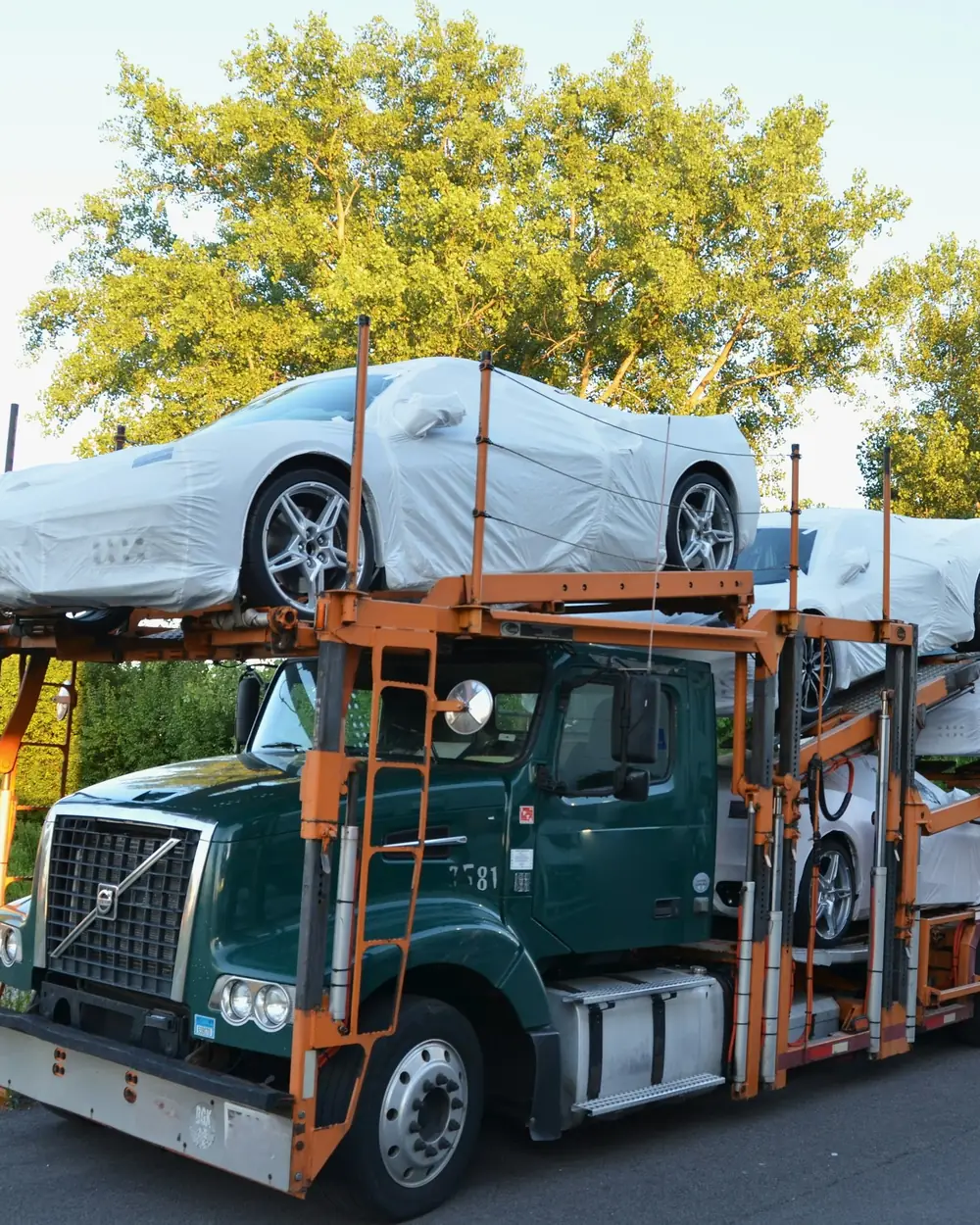 Car hauler loaded with new cars under protective covers