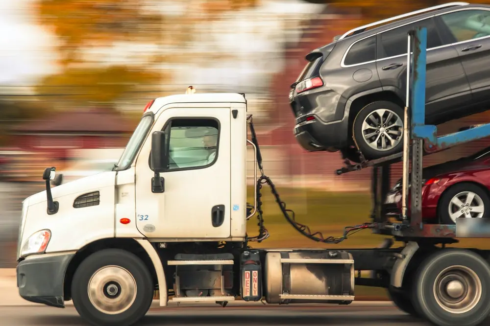 Car carrier truck driving at speed with an SUV on its top deck